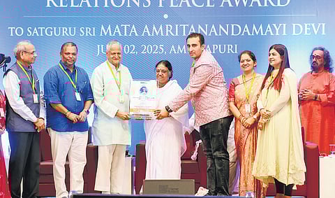 Mata Amritanandamayi receiving the award from Vivekananda International Relations Foundation convener Gagan Malhotra and chief patron Ravikumar Iyer