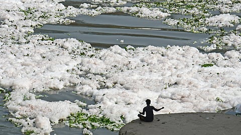 A boy collecting coins using a magnet at Kalindi Kunj.