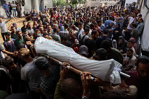Palestinian men carry the body of a person reportedly killed while waiting for aid delivery, during a funeral procession outside al-Shifa hospital in Gaza City,