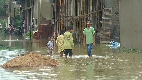 Children wading through a submerged lane in Minnat Nagar of Sundargarh town