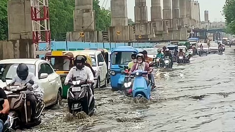 Commuters wade through a waterlogged road after heavy rainfall in several parts of New Delhi, July 4, 2025.