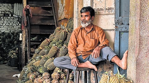 A pineapple seller waits for customers in KR Market, in Bengaluru.