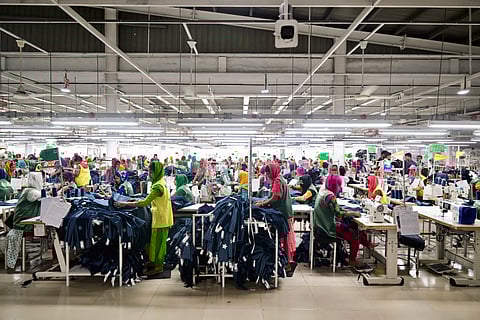 Garment workers tailor clothes at their sewing stations in a garment factory in Tongi, on the outskirts of Dhaka on July 6, 2025.