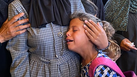 A Palestinian girl is comforted by a relative as she mourns a loved one during the funeral of Palestinians killed in Israeli strikes