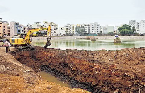 As part of rejuvenation efforts, officials use earthmovers to desilt the Bathukamma Kunta in Bagh Amberpet on Tuesday
