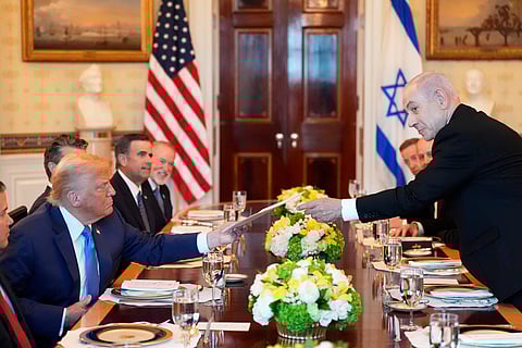 Israel's Prime Minister Benjamin Netanyahu, right, hands President Donald Trump a folder during a meeting in the Blue Room of the White House, Monday, July 7, 2025, in Washington.