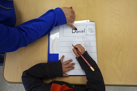 Easterseals Head Start program teaching assistant Tania Ortiz helps a student practice writing his name, Jan. 29, 2025, in Miami.