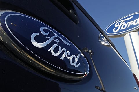 A Ford logo is on the tailgate of a pick-up truck and on a Ford dealership sign in Salem, N.H.