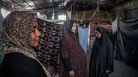 A pregnant Palestinian woman (C) displaced from northern Gaza stands in a warehouse where she is taking shelter in Rafah, in the southern Gaza Strip, on February 29, 2024