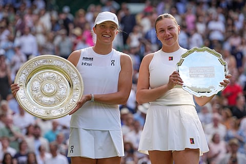 Poland's Iga Swiatek, left, celebrates with the trophy after beating Amanda Anisimova of the U.S., right, to win the women's singles final at the Wimbledon Tennis Championships in London, Saturday, July 12, 2025.