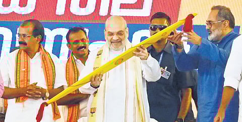 Union Home Minister Amit Shah looks at an ‘Onavillu’ (ceremonial bow) presented to him ahead of the party workers’ meeting at Putharikandam ground in Thiruvananthapuram on Saturday
