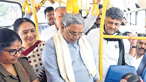 Chief Minister Siddaramaiah hands over a zero ticket to a woman commuter aboard a BMTC bus, as Deputy Chief Minister DK Shivakumar and Chief Secretary Shalini Rajneesh look on, in Bengaluru on Monday