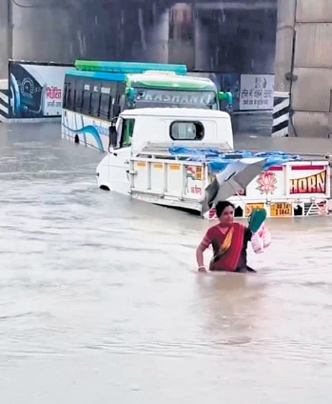 A woman wades through waist-deep water near the underpass at TCI chowk