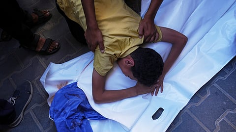 A Palestinian boy mourns over the body of his 12-year-old friend, Abdullah Ahmed, who was killed in an Israeli strike that targeted a drinking water distribution point, at Al-Awda Hospital in Nuseirat, central Gaza Strip, Sunday, July 13, 2025