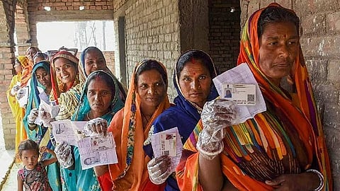 Women holding their Aadhaar cards and voter IDs.