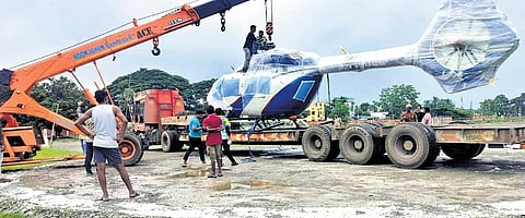 The helicopter being placed on the trailer truck with the help of a crane