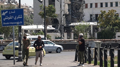 People pass in front of the Syrian Defence Ministry building, which on Wednesday was heavily damaged by Israeli airstrikes in Damascus, Syria, Thursday, July 17, 2025.