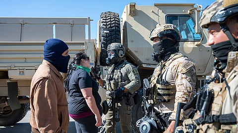 Federal immigration agents talk to Rebecca Torres, second left, after she tried to block a military vehicle during a raid in the agriculture area of Camarillo, Calif., Thursday, July 10, 2025.
