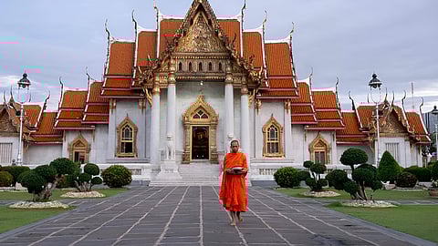 A Buddhist monk prepares to collect alms in front of a temple in Bangkok on July 18, 2025.
