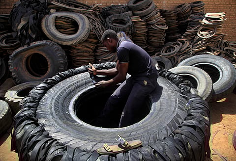 A Sudanese man cuts a heavy duty machine tire into rubber pieces at a shop in a market in Omdurman, Khartoum, Sudan