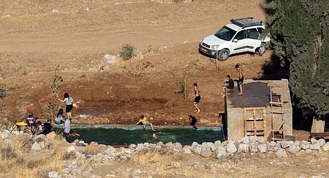 Israeli settlers swim in the Ein Samiyah spring near the village of Kafr Malik, in the Israeli-occupied West Bank, on July 15, 2025.