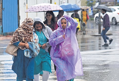Raincoats and umbrellas come out as heavy rain pounds the city on Monday evening.