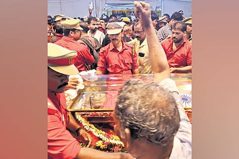 An elderly man raising his fist in solemn tribute to VS