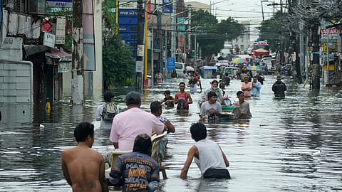 Residents wade along a flooded road as Typhoon Co-may intensified seasonal monsoon rains at Malabon city, Philippines on Friday, July 25, 2025.