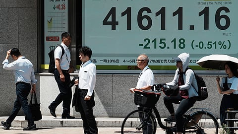 People stand in front of an electronic stock board showing Japan's Nikkei index at a securities firm Friday, July 25, 2025, in Tokyo.