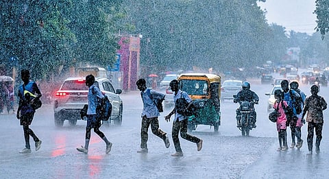 Students returning from school run for cover in Madhusudan Marg as incessant rain lashes Bhubaneswar on Friday.