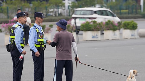 Police officers talk with a man walking his dog in front of the "Zhuhai People's Fitness Plaza," where a man deliberately rammed his car into people exercising at the sports center, killing some and injuring others in Zhuhai, southern China's Guangdong province, on Nov. 13, 2024.