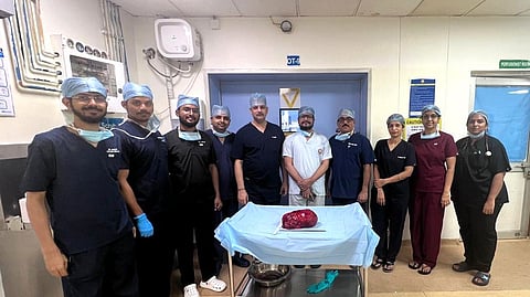 Surgeons with the patient and the removed tumour.