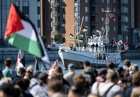 Demonstrators carrying Palestinian flags look on as the Ship to Gaza boat 'Handala' arrives at the port of Malmö, Sweden, Wednesday, May 8, 2024.