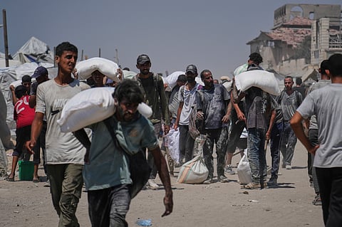 Palestinians carry sacks of flour unloaded from a humanitarian aid convoy that reached Gaza City from the northern Gaza Strip.