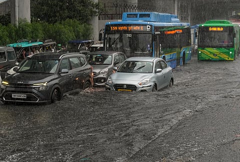 Commuters wade through a waterlogged road during rainfall, in New Delhi, Tuesday, July 29, 2025.