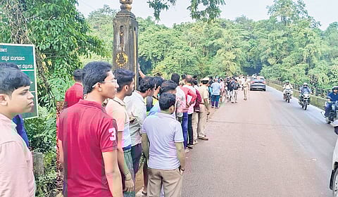 Curious onlookers gather at a bridge across the Nethravathi river, as police personnel look for human skeletal remains in the vicinity, on Thursday.