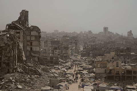 People walk down a street surrounded by buildings destroyed by Israeli bombardments in the Gaza Strip, Tuesday, July 29, 2025.