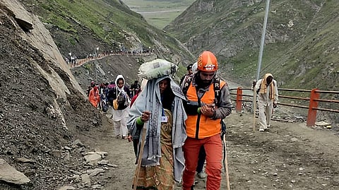 A member of the Jammu and Kashmir Police's Mountain Rescue Team (MRT) helps a pilgrim during the annual 'Amarnath Yatra' at Sangam Top, in Anantnag district, Jammu and Kashmir, Friday, Aug. 1, 2025.