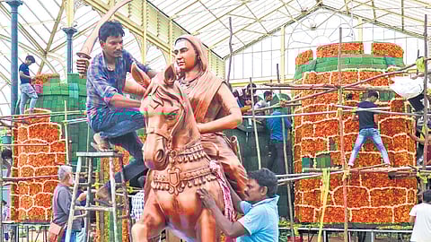 Workers install a statue of Kittur Rani Chennamma in the Glass House, ahead of the Independence Day Flower Show, at Lalbagh on Tuesday