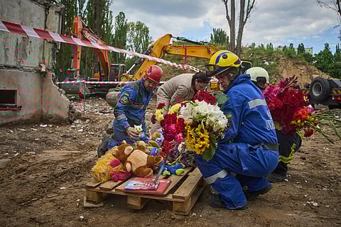 Rescuers lay toys and flowers on the site of Russia's Thursday night missile strike that hit a multistory residential house killing 31 civilians including five children in Kyiv, Ukraine, Friday, Aug. 1, 2025.
