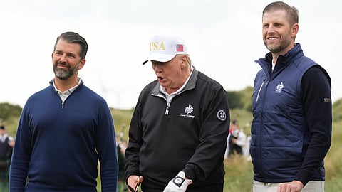 President Donald Trump cuts the ribbon, standing between Donald Trump Jr., left, and Eric Trump, during an opening ceremony for the Trump International Golf Links golf course, near Aberdeen, Scotland, Tuesday, July 29, 2025.