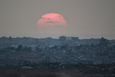 The sun sets behind buildings that were destroyed during the Israeli ground and air operations stand in the northern Gaza Strip as seen from southern Israel, Friday, Aug. 8, 2025.