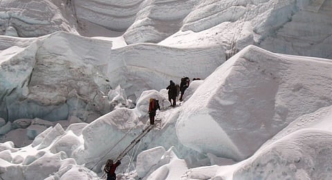 A team from the Mount Everest expedition negotiates a cliff of vertical ice, rock, and glacier.