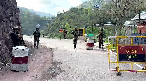 Indian Army personnel stand guard on a road in Uri sector.