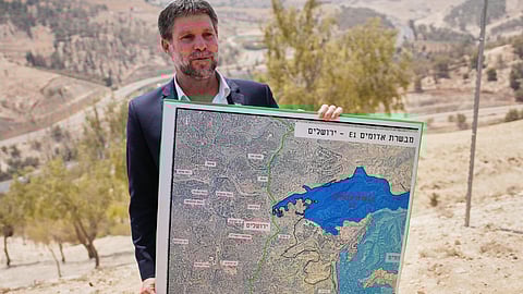 Israeli Finance Minister Bezalel Smotrich holds a map that shows the E1 settlement project during a press conference near the settlement of Maale Adumim, in the Israeli-occupied West Bank, Thursday, Aug. 14, 2025.