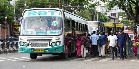 A private bus stops in the middle of the busy railway junction road in Tiruchy, causing traffic congestion and inconvenience to commuters.