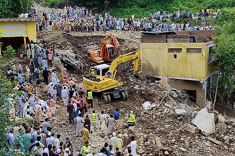 Local residents watch rescue workers search for victims in the rubble of damaged homes following Monday's flash flooding in Dalori village in Swabi, a district of Pakistan's Khyber Pakhtunkhwa province, Tuesday, Aug. 19, 2025.