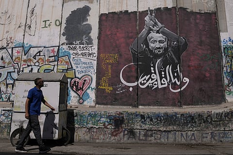 A man walks past a mural depicting the Palestinian leader Marwan Barghouti, with a message that reads in Arabic, "See you soon", on Israel's separation barrier in the West Bank city of Bethlehem, Wednesday, Aug. 20, 2025