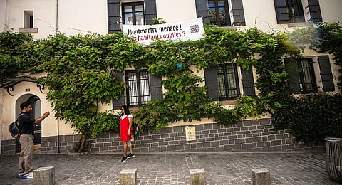 A banner reading "Montmartre under threat. Are residents being forgotten?" hangs at windows in the Montmartre district in Paris, France, Monday, Aug. 4, 2025.