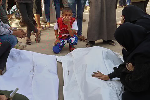 A Palestinian boy mourns over the bodies of his uncle, Mohammad Harb and his cousin Leen Harb, who were killed in an Israeli airstrike, during their funeral at Nasser Hospital, in Khan Younis, in the southern Gaza Strip, Tuesday, Aug. 19, 2025.